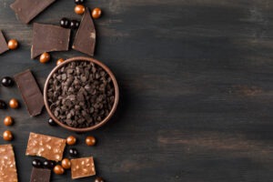 choco-drops-with-chocoballs-and-choco-bars-in-clay-bowl-on-wooden-table